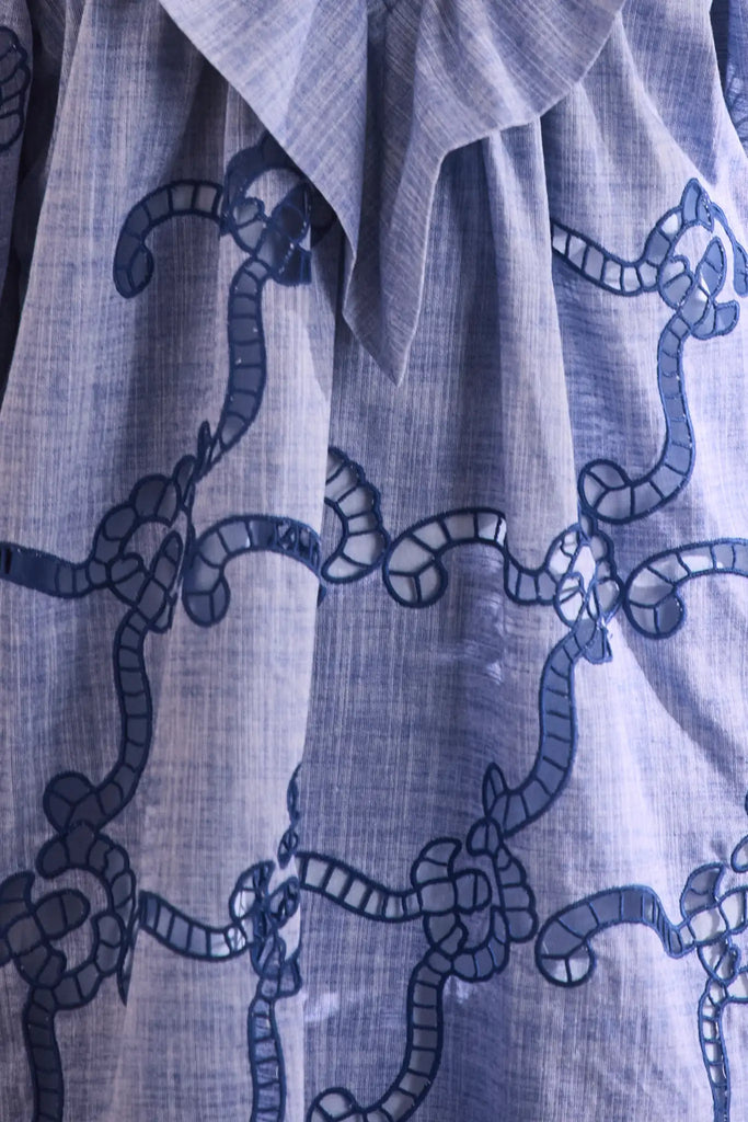 Blue cut-out embroidered linen, crew neckline, softly ruffled yoke, long sleeves with button cuffs