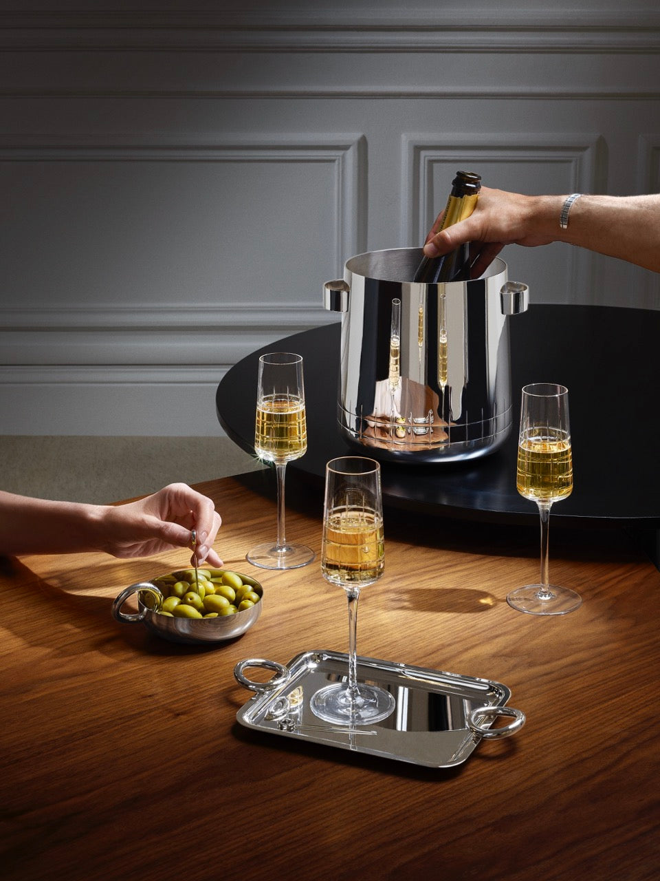 Front view of Graphik silver-plated champagne cooler with mirror polish, geometric engraving, and side handles on wooden table