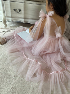Girl wearing Camila blush pink tulle gown with flutter sleeves and floor-length skirt for formal occasion.