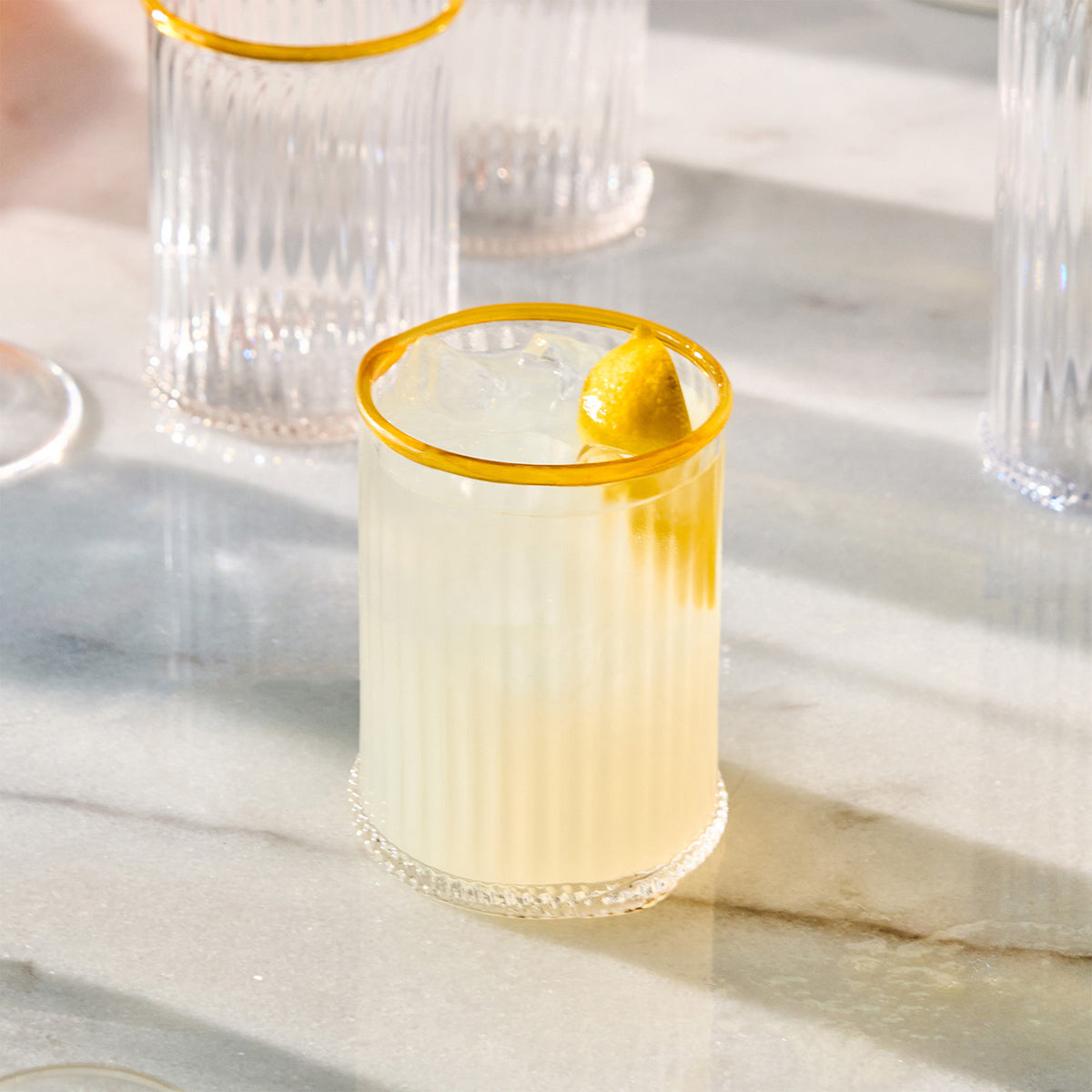 Front view of Nell Double Old Fashioned in Daffodil showcasing its yellow rim and textured glass on a marble surface