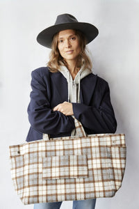 Woman holding a plaid tote bag against a plain background