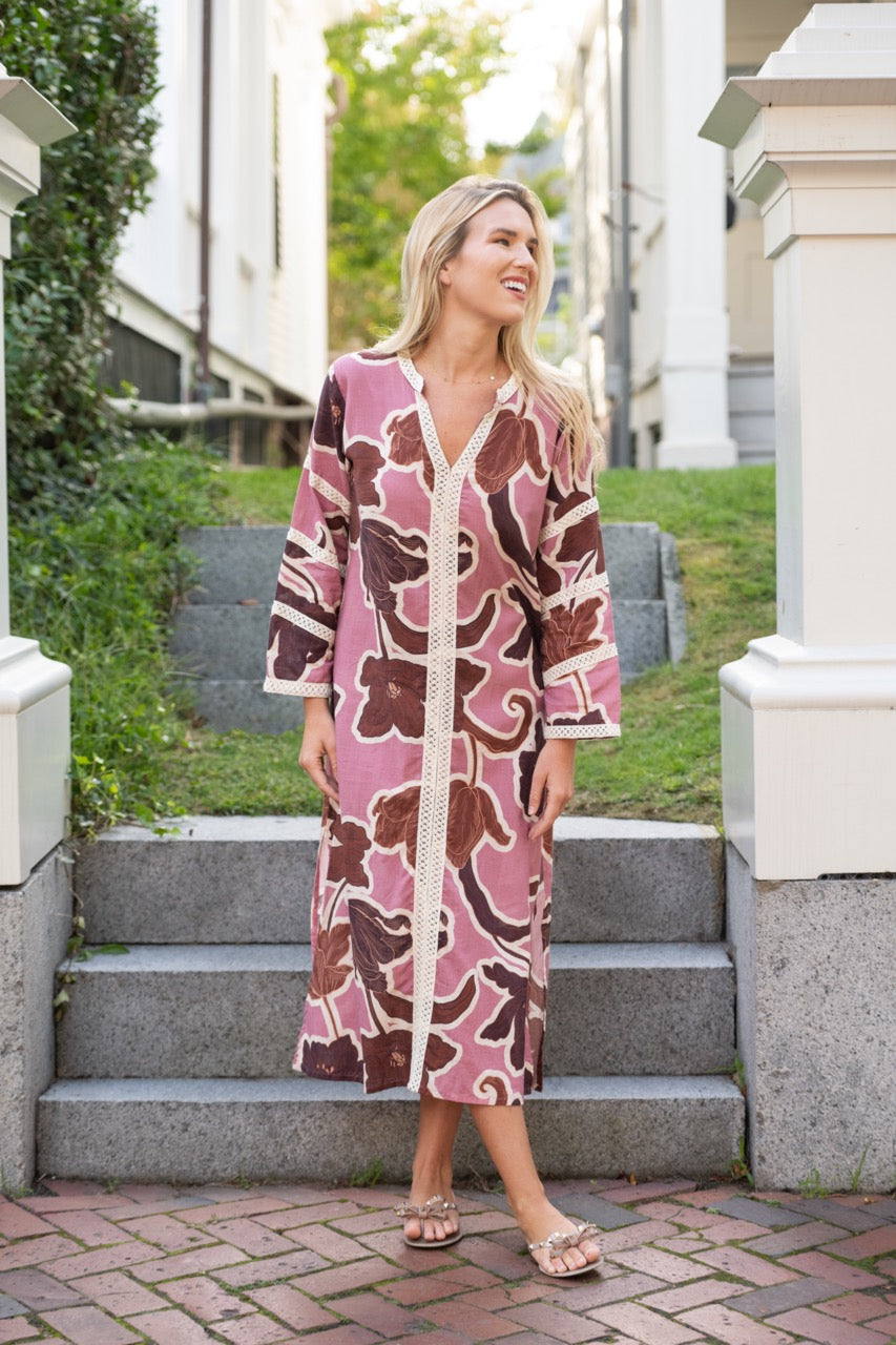 Front view of Bardot Merrain pink floral cotton kaftan showcasing V-neck, cotton lace trim and side split on model on outdoor stone steps