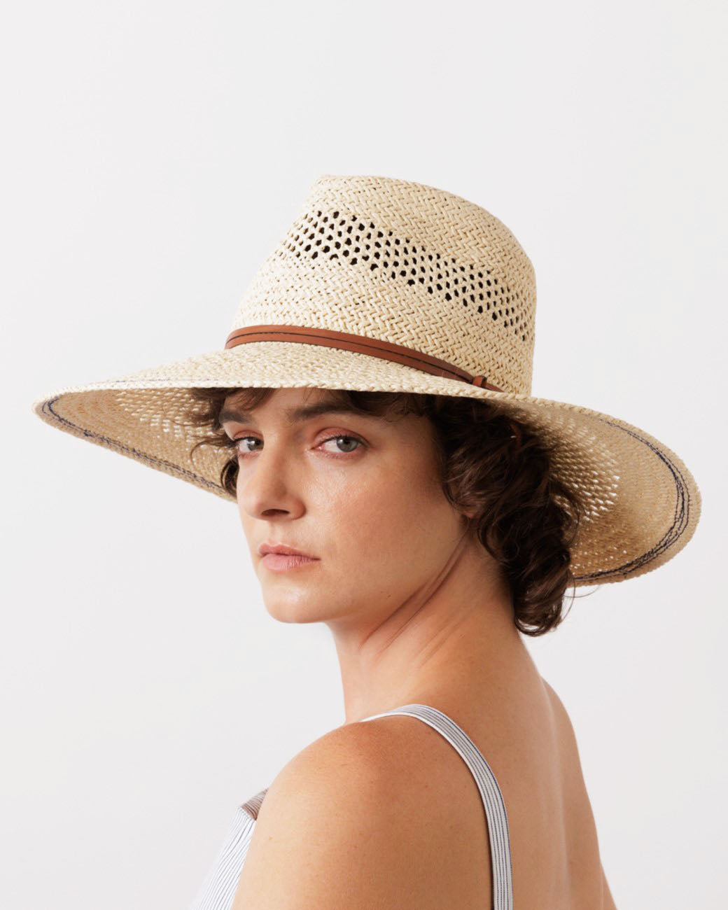 Three-quarter view of Batea Hat in Bleach showcasing its lacy straw pattern, leather strap, and wide brim on a model