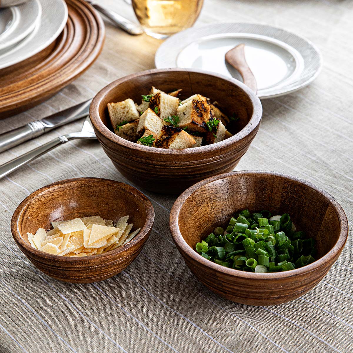 Close-up view of Bilbao Wood Nesting Bowls showcasing mango wood bowls holding snacks and garnishes on a table setting