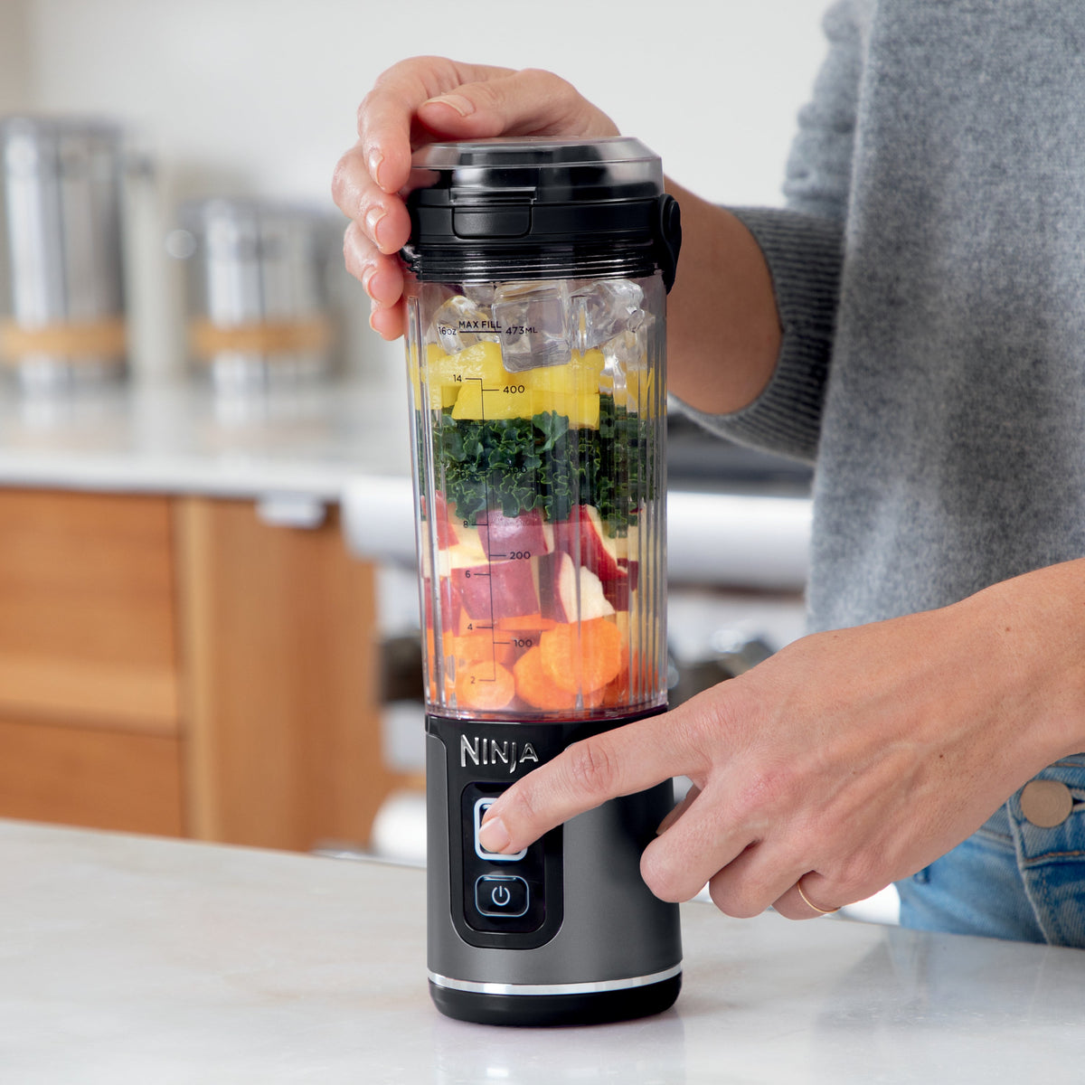 Front view of Blast Portable Cordless Blender in Black showcasing ingredients and 16 oz markings in a kitchen