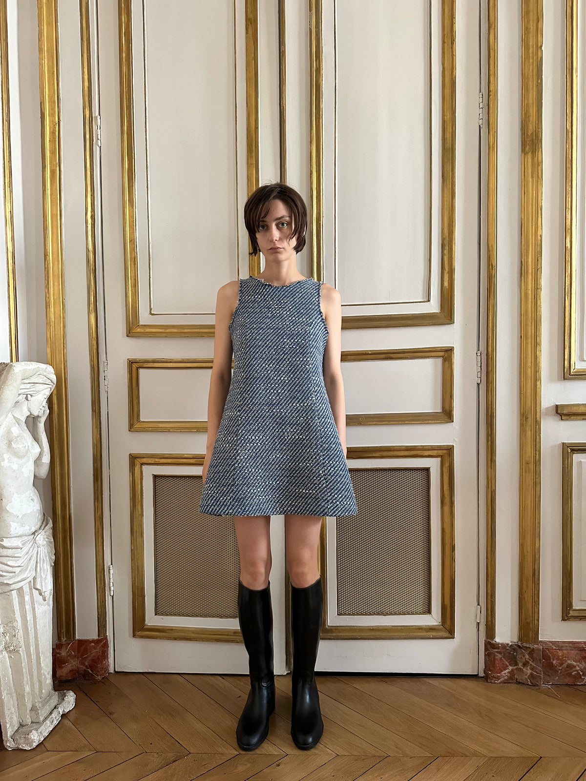 Front view of Jane dress in Mariner showcasing sleeveless A-line tweed silhouette with gold-trimmed door background
