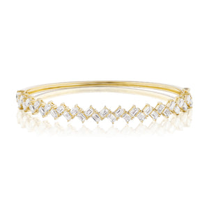 The Zig Zag Motif Emerald Cut Diamond Bangle showcases a row of emerald cut diamonds in a zigzag design, crafted from polished 18k gold with a sleek, reflective finish.