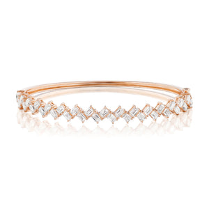 The Zig Zag Motif Emerald Cut Diamond Bangle is a rose gold bracelet featuring two rows of angular, emerald-cut white diamonds with VS clarity in a zig-zag pattern atop a smooth polished band.