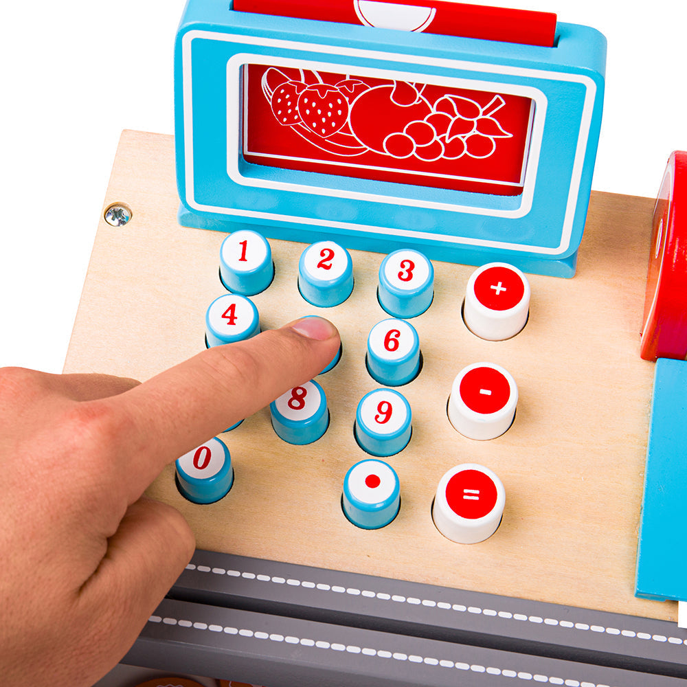 Close-up of wooden toy till keypad showcasing numbered buttons, plus, minus and equals keys with a finger pressing a button on a white background