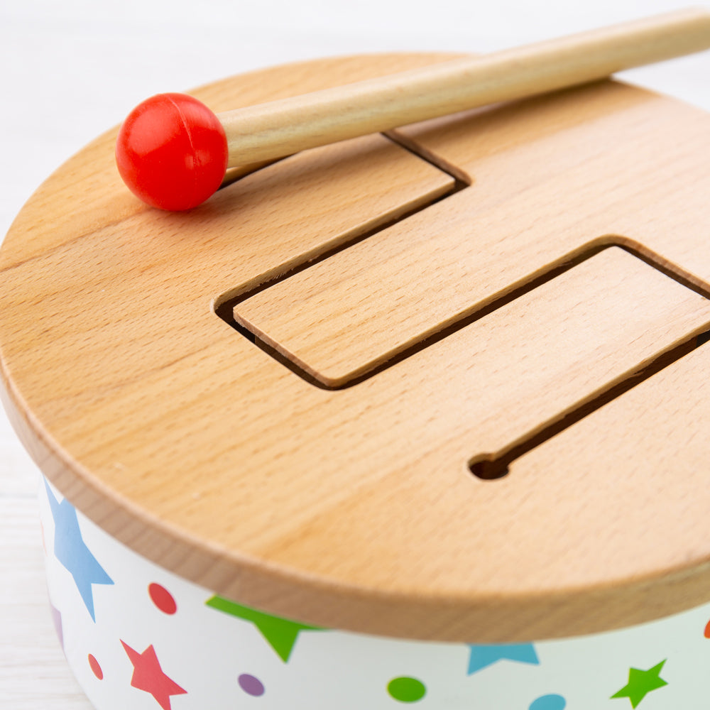 Close-up of Wooden Drum showcasing cut-out sound holes and mallet with a white background
