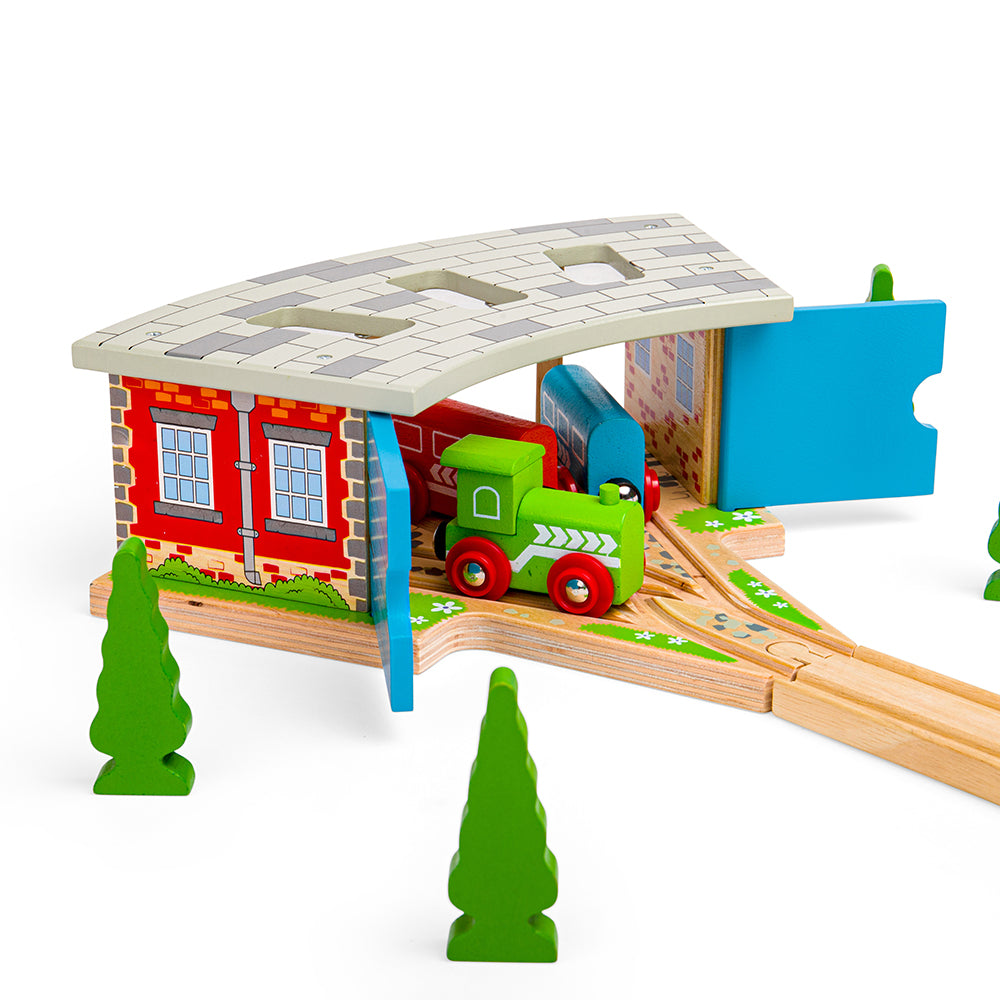 Three-quarter view of Triple Engine Shed wooden train shed showing three-bay roof, hinged blue doors, green engine on track