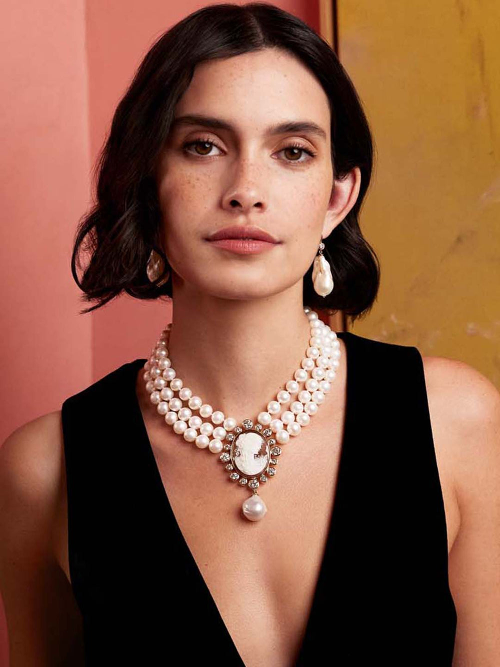 Front view of baroque pearl drop earrings on model showing asymmetrical pearls and diamond accents against pink backdrop