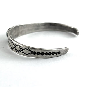 Side view of vintage single stone bracelet showcasing an engraved sterling silver cuff with open ends on a white background