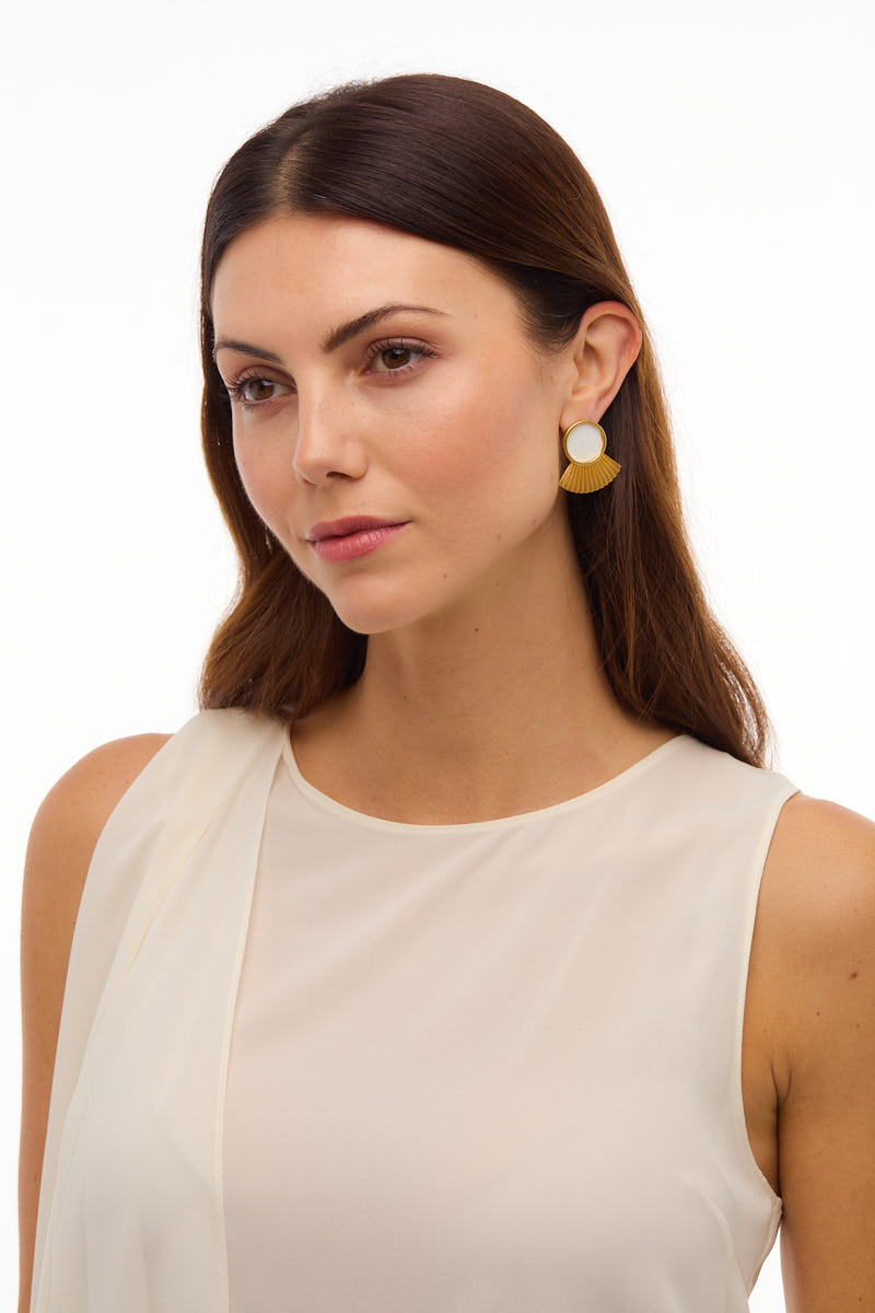 Three-quarter view of Acklins stud earring on model showcasing round white center and gold feather fan on white background