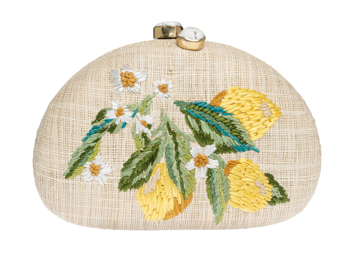 Front of Berna Clutch in natural raffia showcasing yellow embroidered lemons, green leaves and ivory stone clasp