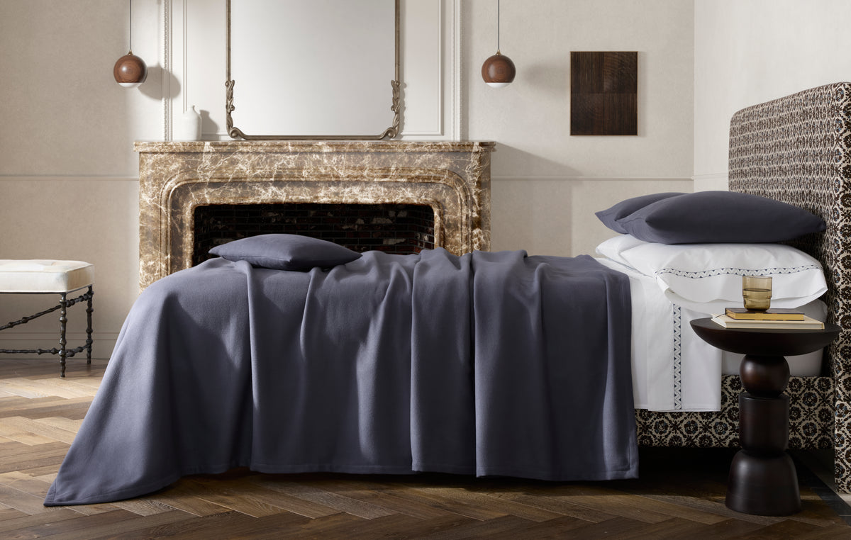 Dream Modal blanket in Ink draped over a bed in a styled bedroom with marble fireplace