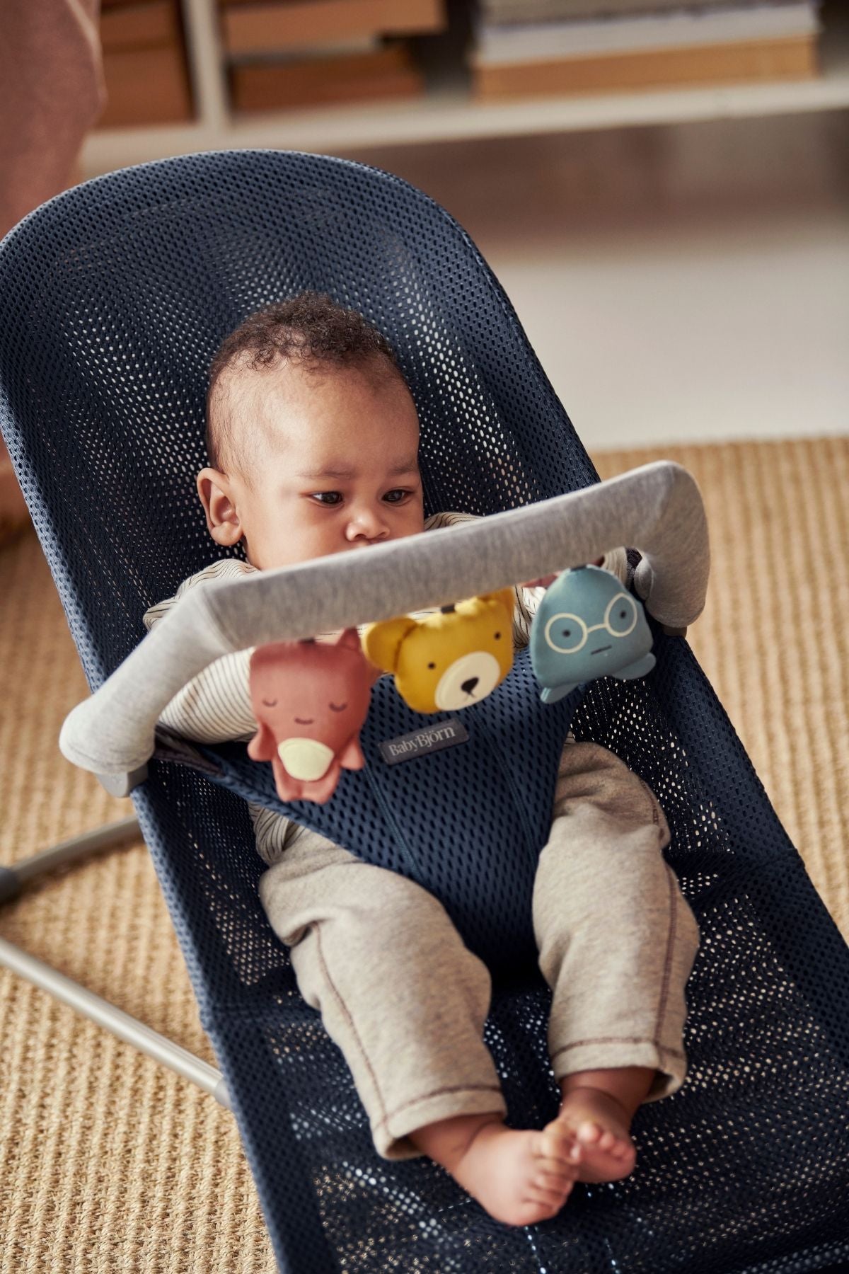 Front of Toy for Bouncer in Soft Friends with three hanging plush toys on a gray bar attached to a navy bouncer