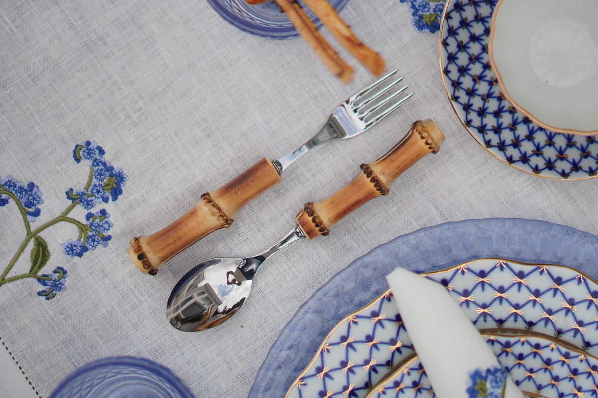Bamboo-handled flatware arranged with patterned dishes on a tablecloth