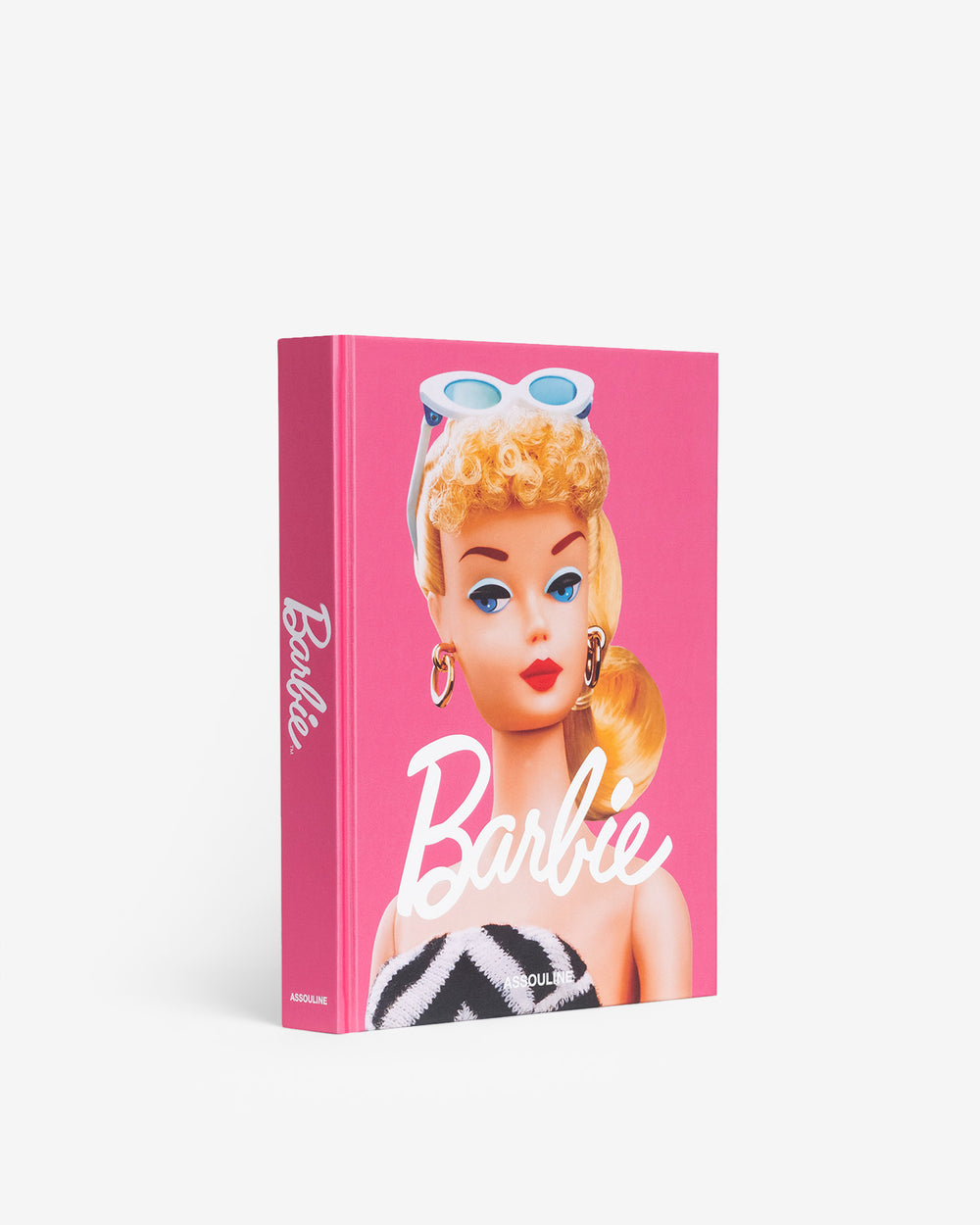 Angled view of Barbie hardcover book with pink cover, vintage doll portrait, and large white Barbie title on white