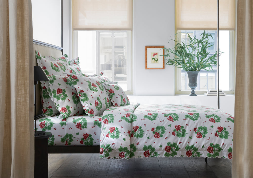 Bed styled with Geranium pillowcase set and matching duvet showing red and green floral print on white in a bright bedroom