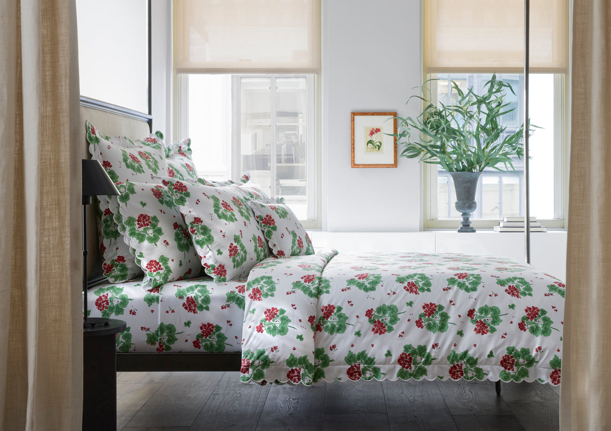 Bed styled with Geranium pillowcase set and matching duvet showing red and green floral print on white in a bright bedroom