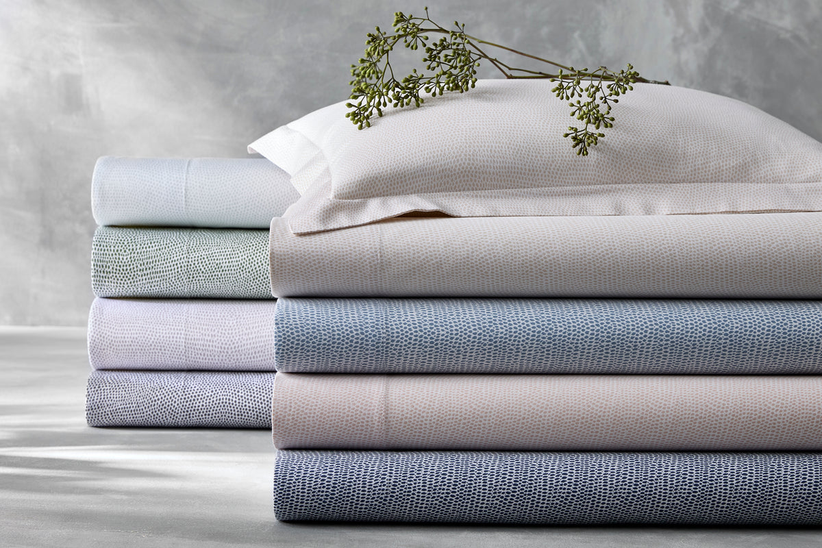 Front view of The Jasper Collection folded sheets showing small pebble-like textured weave in pastel blue, pink, and green on a neutral gray background