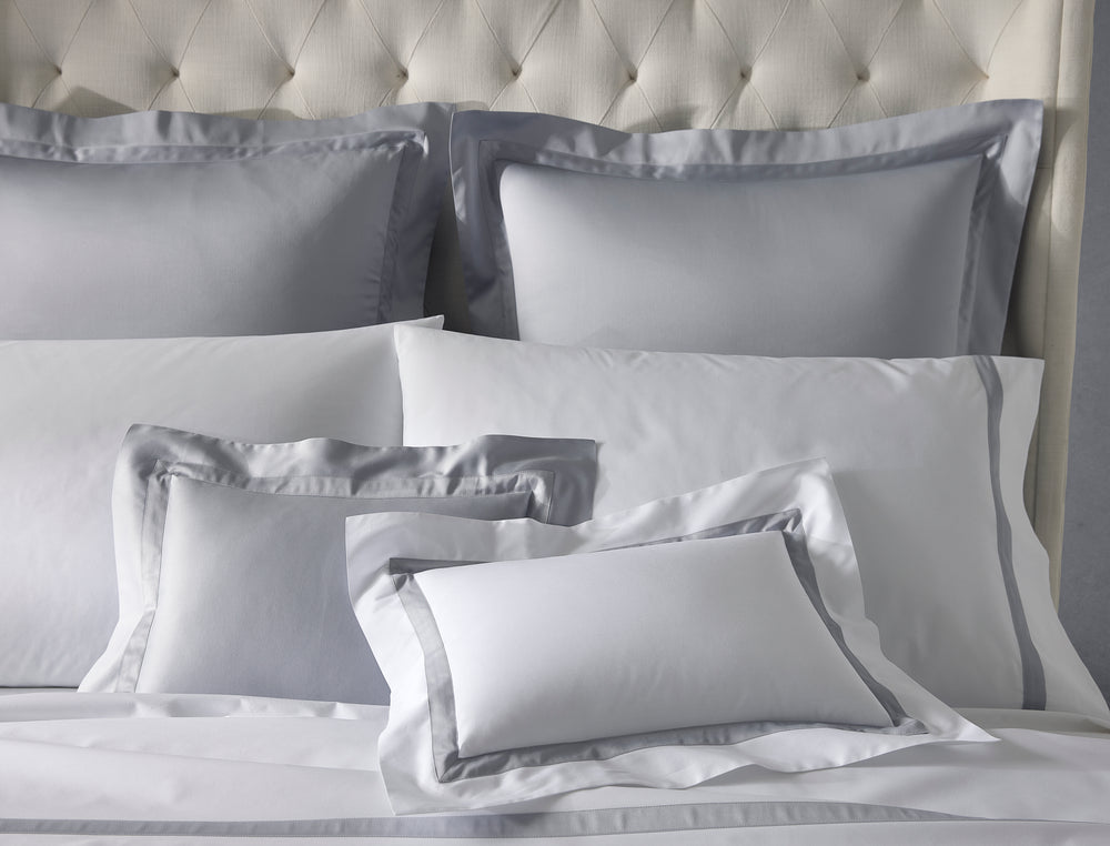 Front view of Nocturne sham in dove showing contrast gray border and sateen finish on a tufted headboard