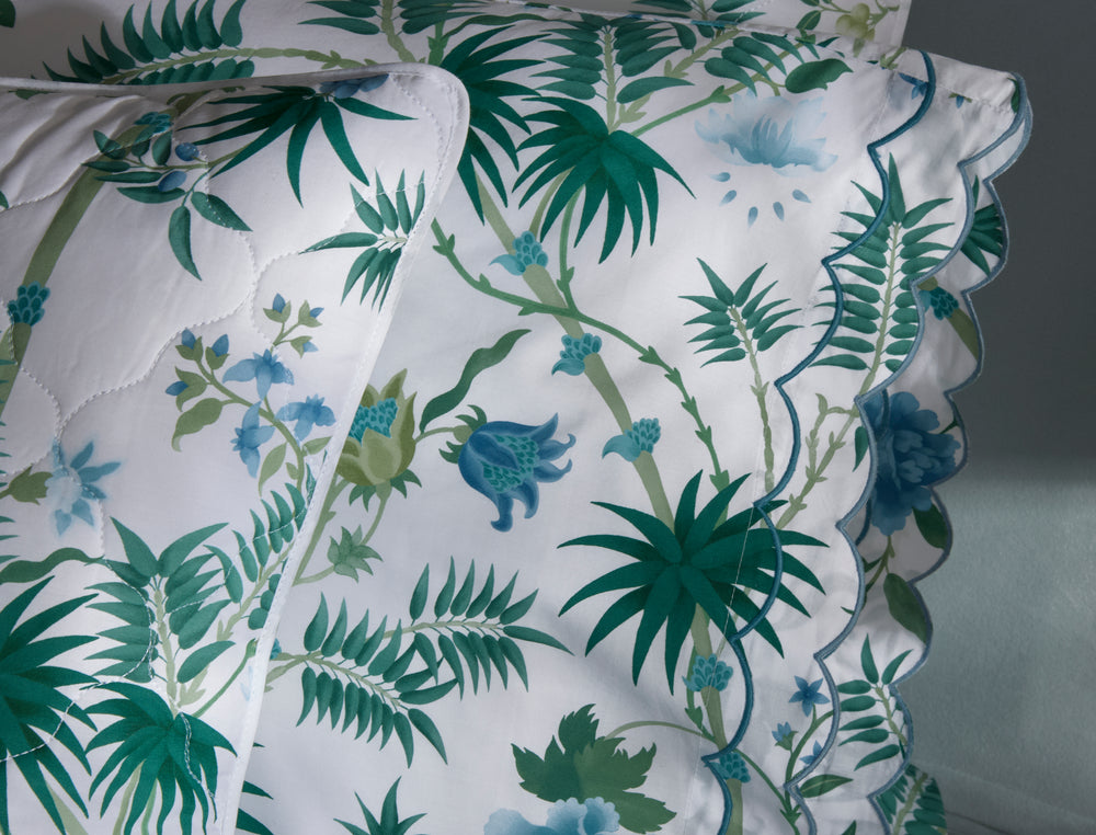 Close-up of Palmyra pillowcases showcasing emerald palm-frond print and scalloped embroidered edge on white background