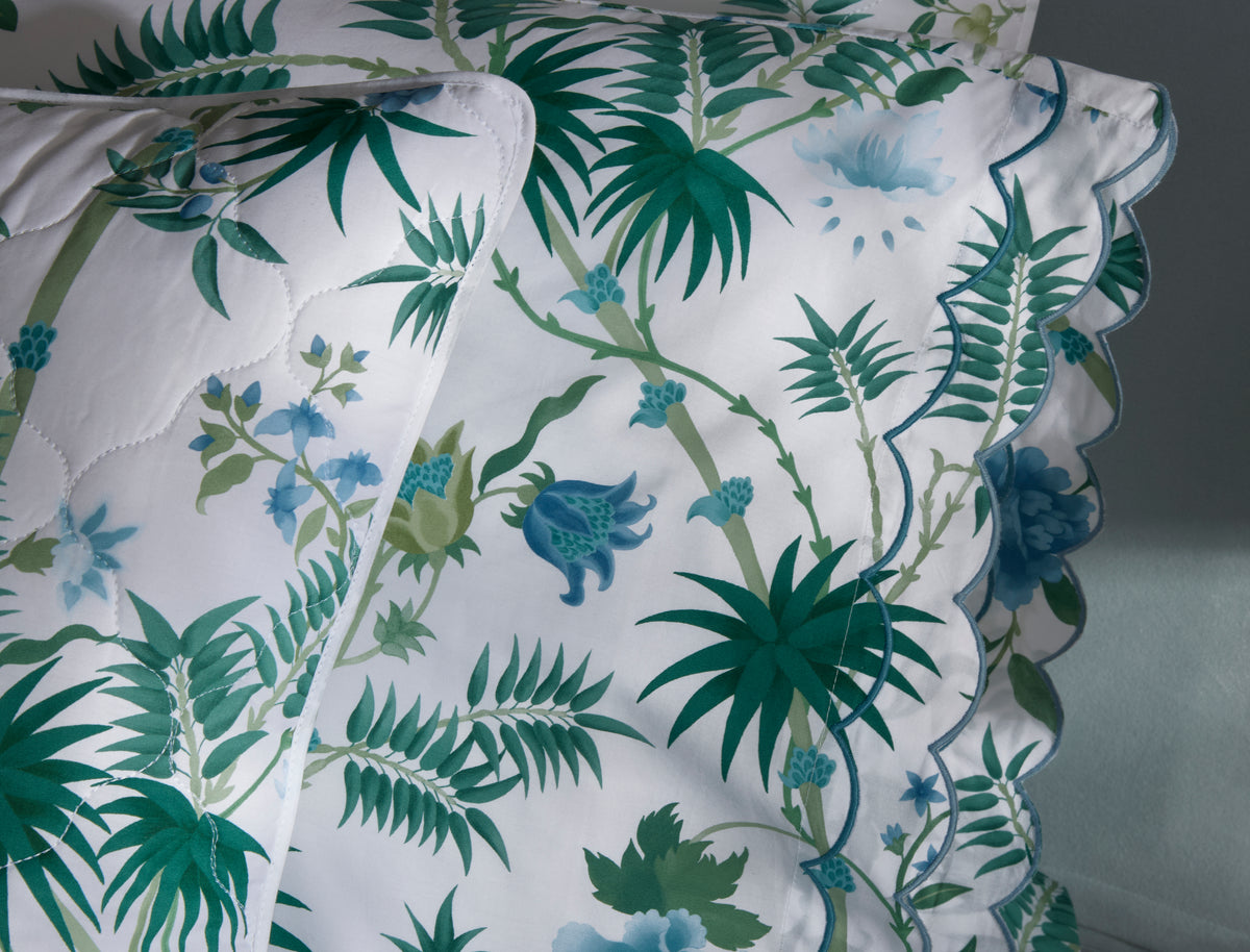 Close-up of Palmyra pillowcases showcasing emerald palm-frond print and scalloped embroidered edge on white background