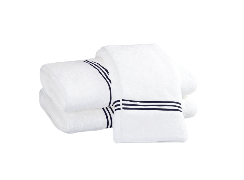 Front view of three stacked white bath towels showcasing navy triple stripe border on white background