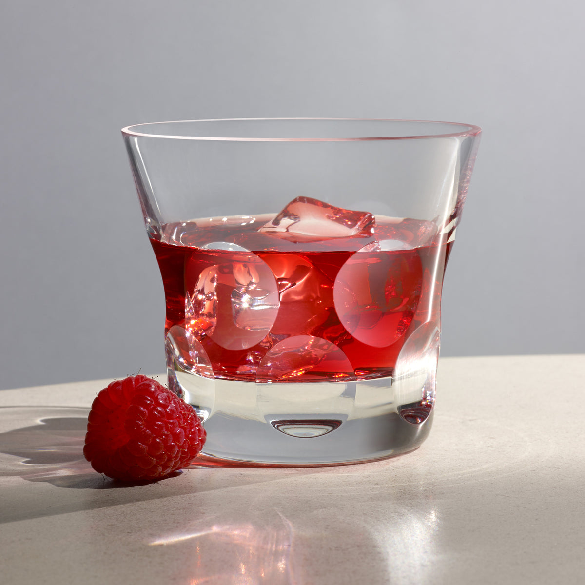 Front view of Beluga Double Old Fashion Tumbler #2, Set of 2 showcasing circular base motif with red drink, ice, raspberry