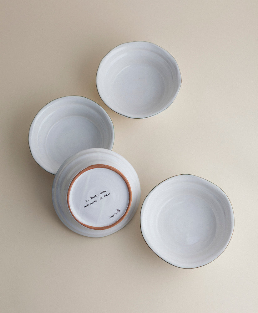 Top-down view of four Bevagna soup bowls in white glazed terracotta with one flipped to show Il Buco Vita mark