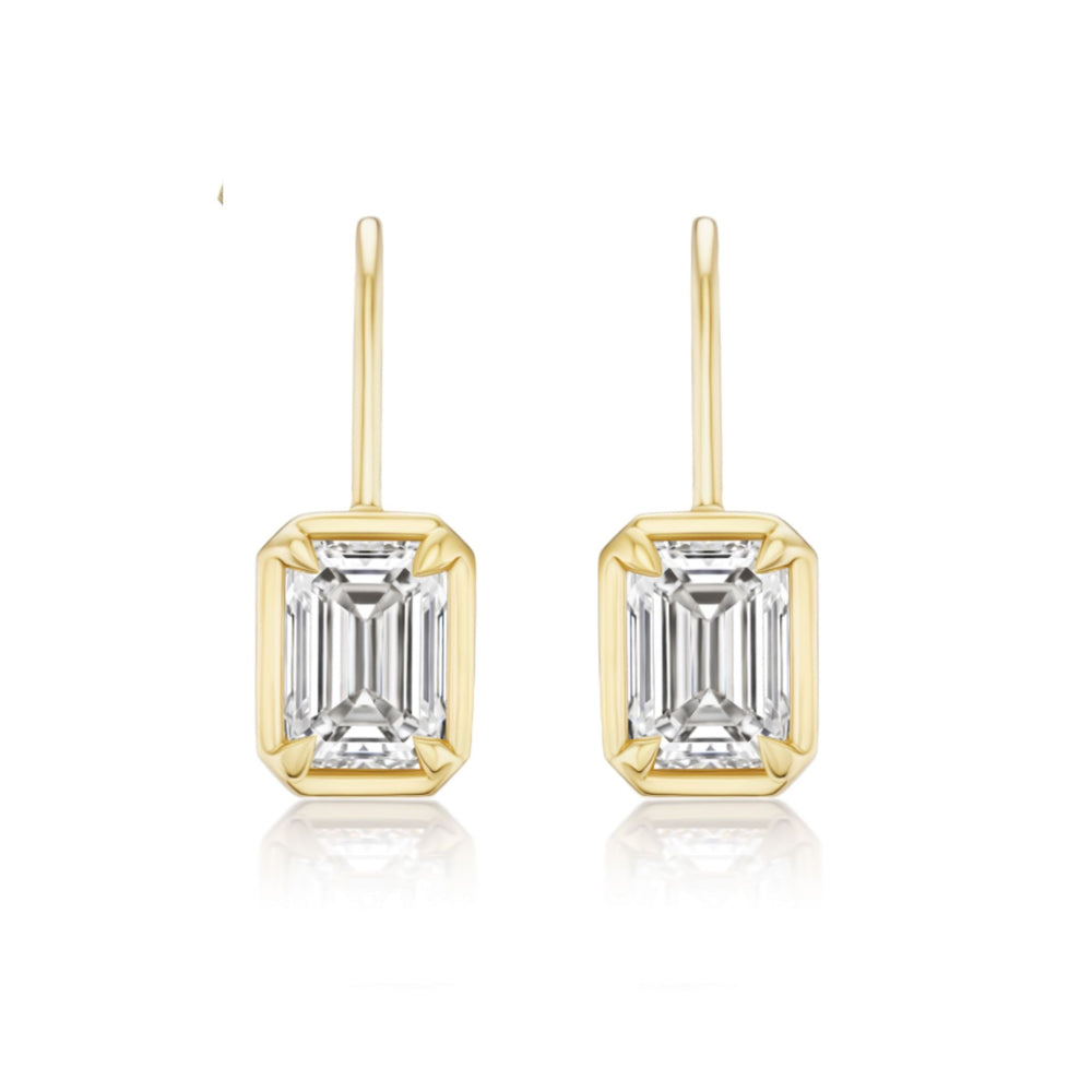 The Bezel Set Emerald Cut Diamond Ear Jacket in Yellow Gold features J-color emerald cut diamonds in rectangular gold frames, shown on a white background.