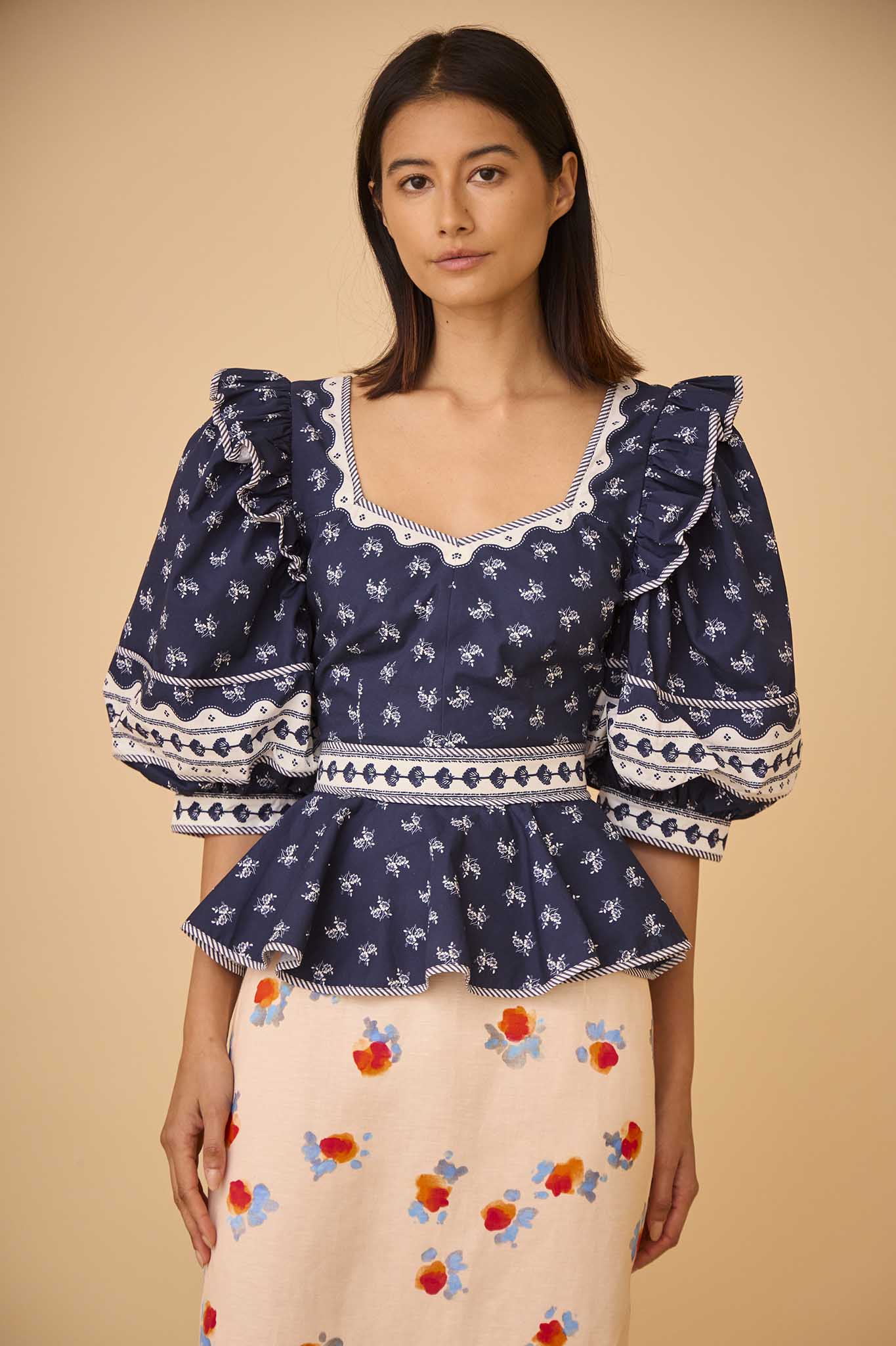 The Blayne Top has a princess neckline, oversized puff sleeves, a cinched waist, and a peplum hem. 
