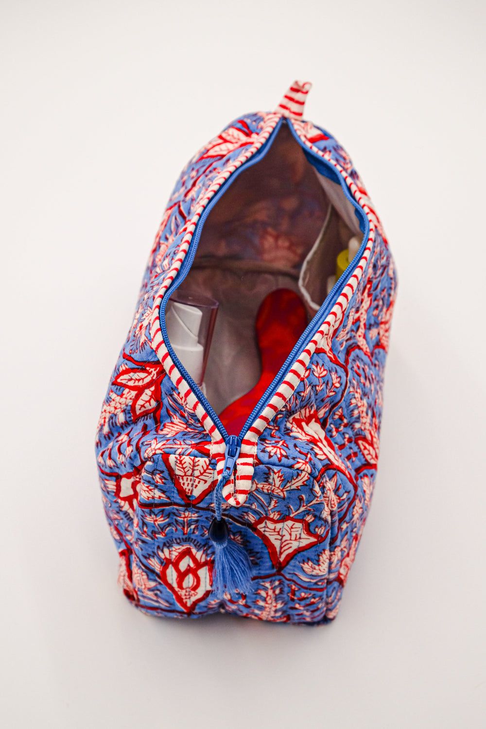 Top-down view of Blue Arch Toiletry Bag showing wipeable liner and interior pockets, blue-red block-print cotton