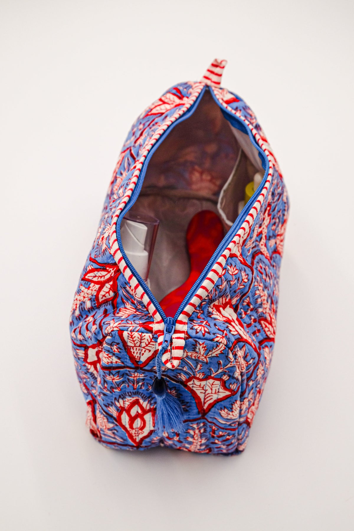 Top-down view of Blue Arch Toiletry Bag showing wipeable liner and interior pockets, blue-red block-print cotton