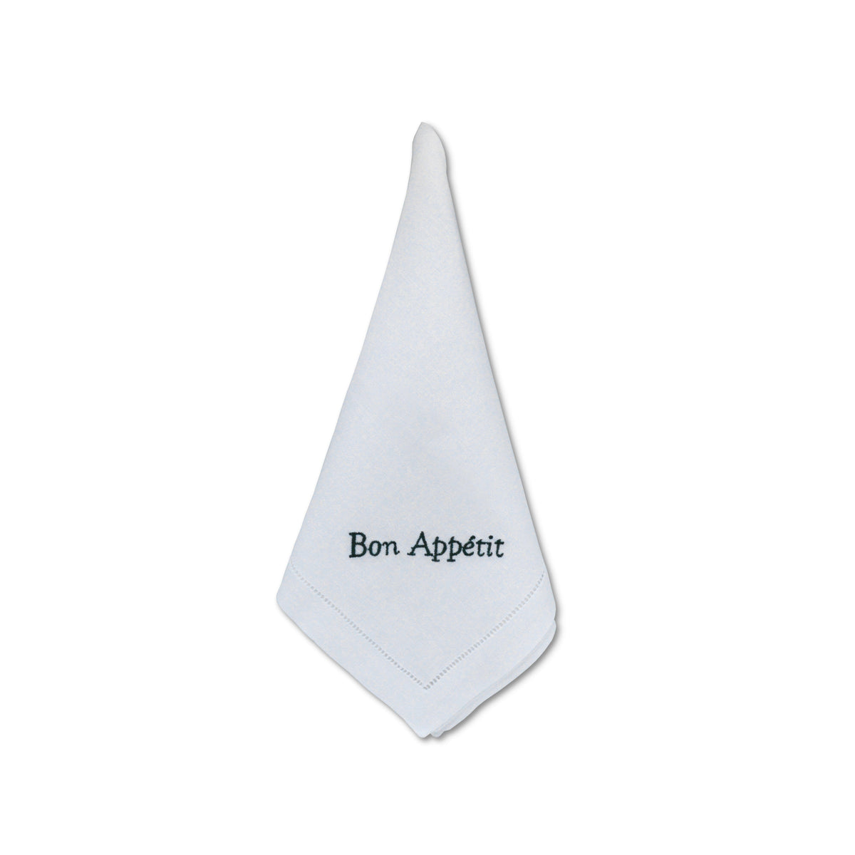 Folded white linen dinner napkin embroidered with “Bon Appétit” in green thread and hemstitch border on white background