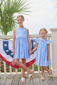 Little English traditional children's clothing. Flutter sleeve dress for toddler girls in royal blue mini gingham with smocking at the collar and American flag bunting