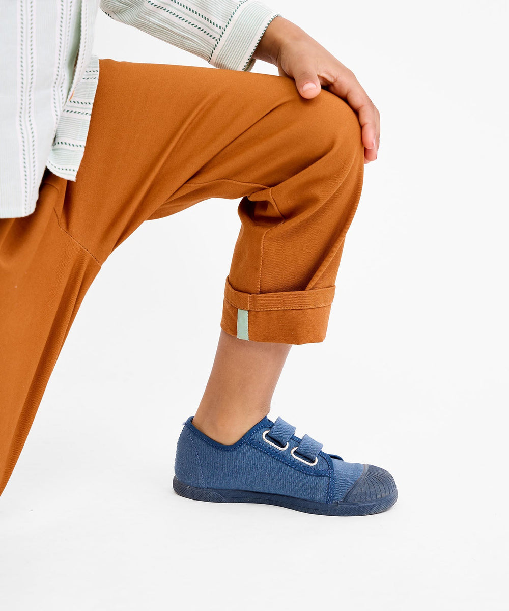 Close up side view of Bowie Pant in Pecan on child model showcasing cuffed hem with mint contrast tab against white background