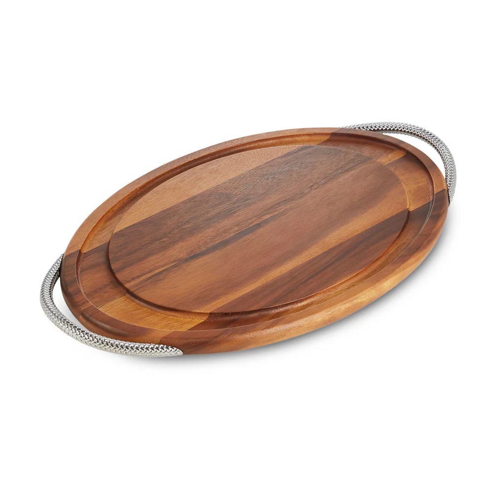 Angled top view of Braid Carving Board showing acacia wood surface, juice groove, and braided chrome handles on white background