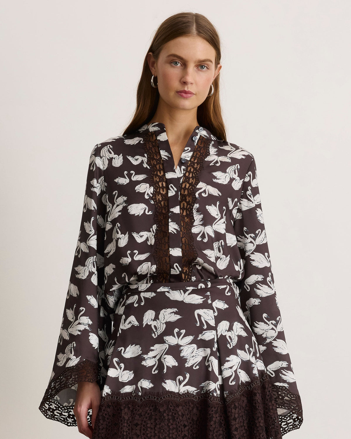 Front view of Brielle Top in Dark Fig Swan showcasing swan print, button-up front, lace trim, and bell sleeves with a light gray background