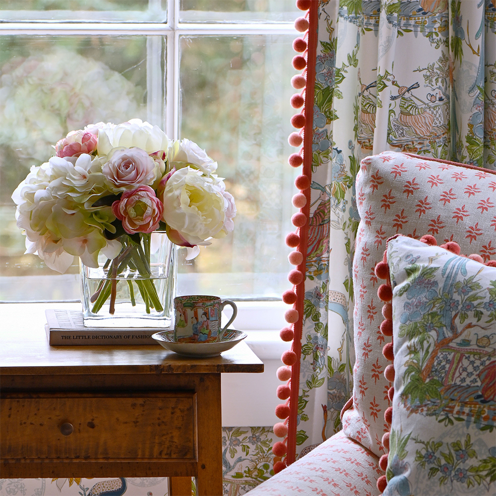 Front view of Bright Young Thing with cream and pink hydrangeas, roses, and ranunculus in a glass cube by a window