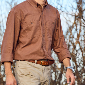 A person in a Tom Beckbe Dixon Brushed Cotton Twill Shirt, khaki pants, and a watch stands before leafless trees.