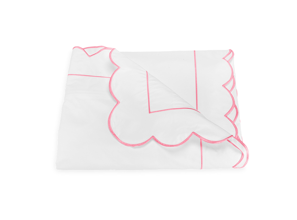 Folded Butterfield duvet cover top view showing scalloped pink embroidered edge and corner detail on white background