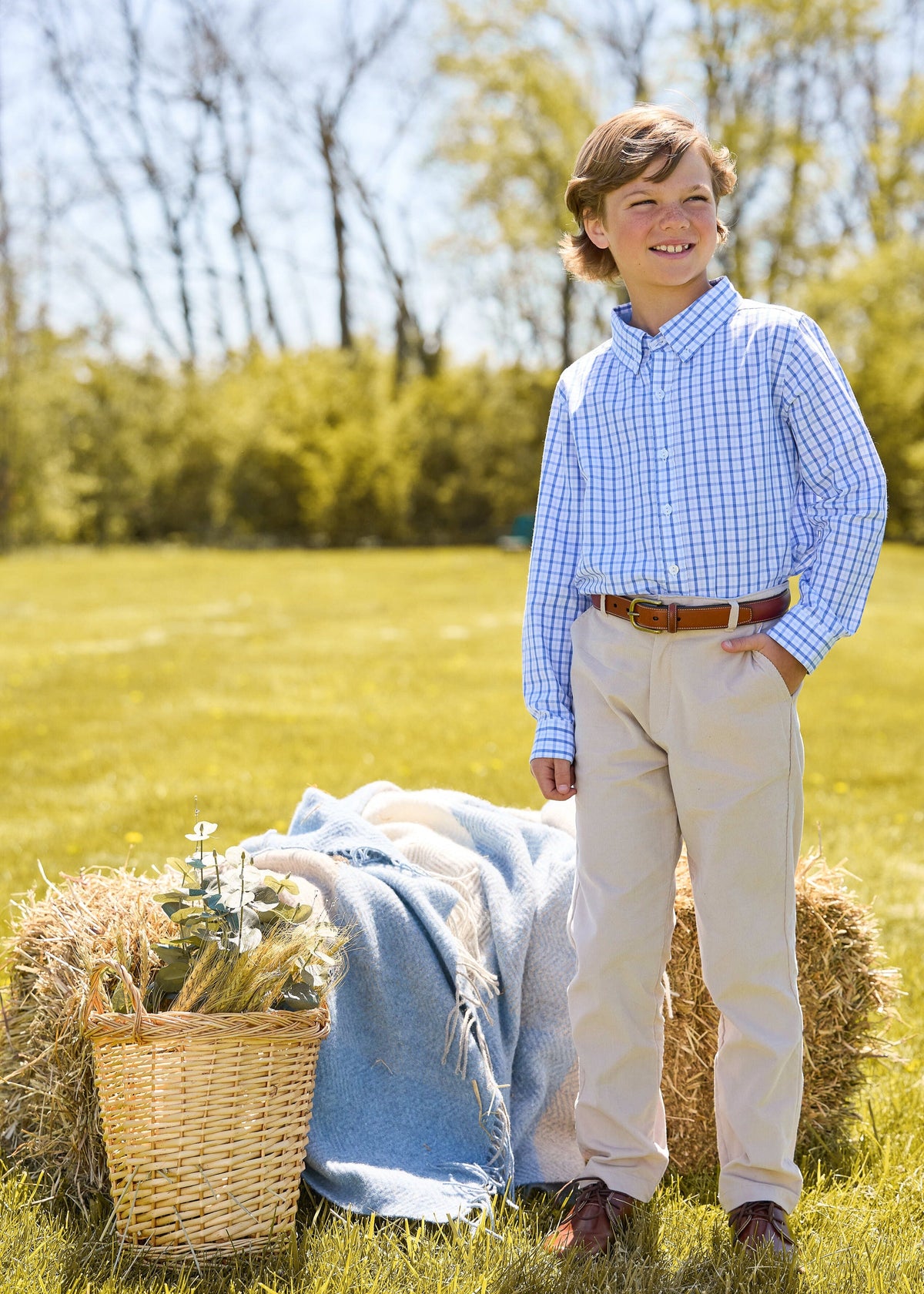 Three-quarter view of Button Down Shirt in Woodberry Plaid on a boy, showing blue-white plaid and modern fit in an outdoor field