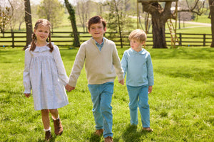 Little English traditional children's clothing.  Classic long sleeve peter pan shirt in blue Alpine Gingham paired with blue Alpine Corduroy pull on pants for toddler boys.  Older boys gray quarter zip sweater layered over blue Alpine Gingham button down shirt and paired with blue Alpine Corduroy classic pants. Ruffled collar long sleeve Bespoke Dress for little girls in blue and green Waterbury Floral