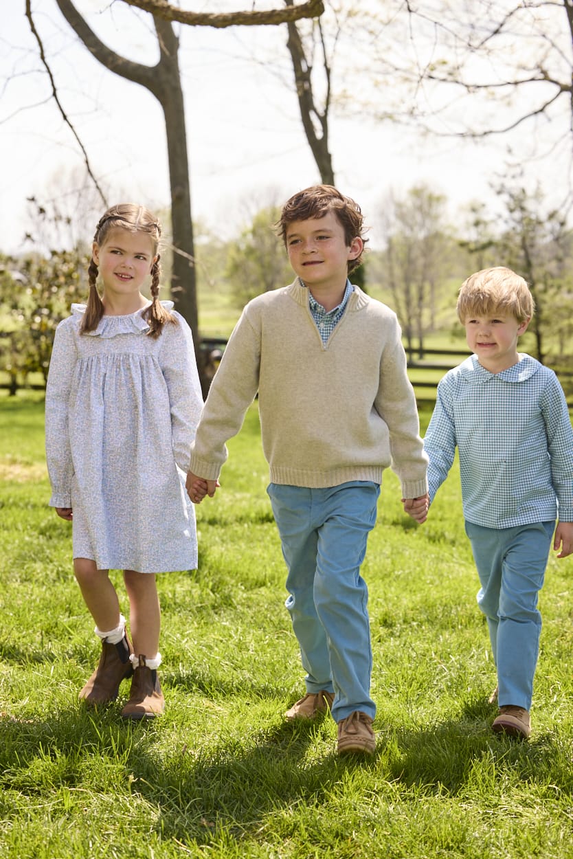 Little English traditional children's clothing.  Classic long sleeve peter pan shirt in blue Alpine Gingham paired with blue Alpine Corduroy pull on pants for toddler boys.  Older boys gray quarter zip sweater layered over blue Alpine Gingham button down shirt and paired with blue Alpine Corduroy classic pants. Ruffled collar long sleeve Bespoke Dress for little girls in blue and green Waterbury Floral