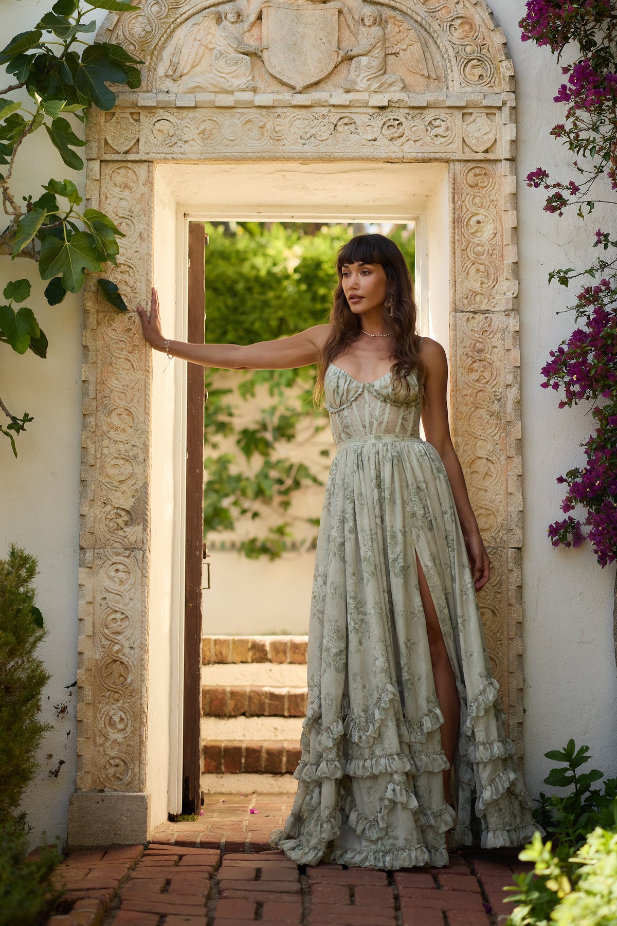 Front view of The Carmen Dress in Sage Tapestry showcasing corset bodice, floral chiffon, side slit, and ruffled hem