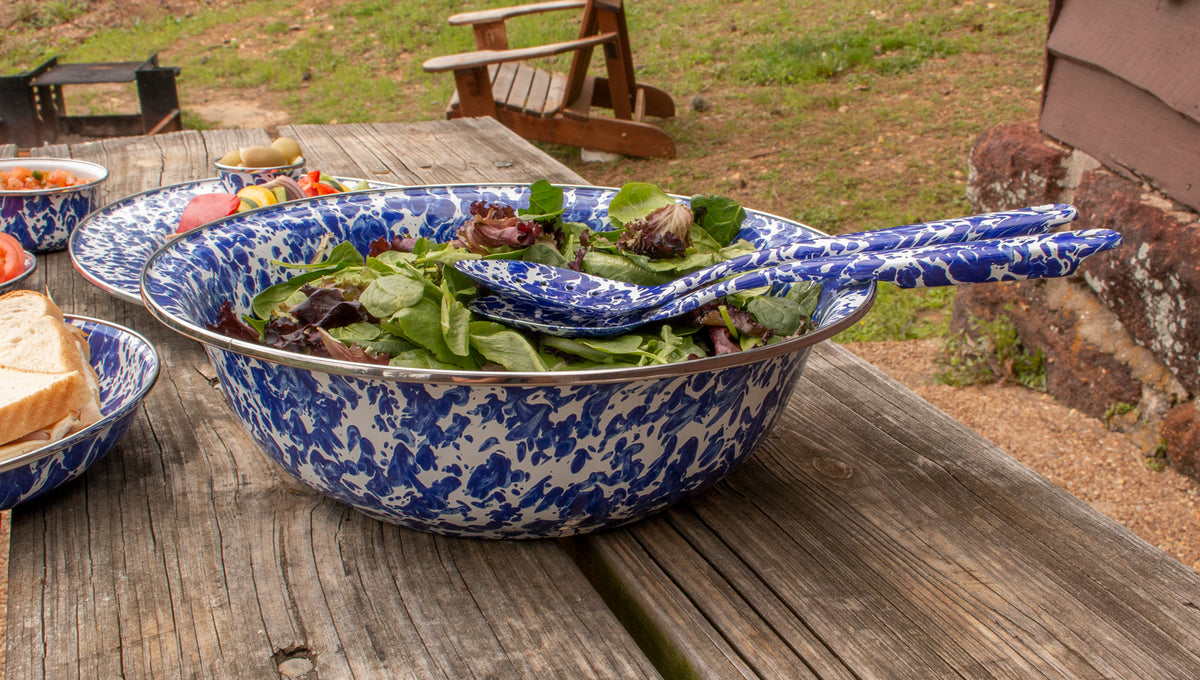Close-up of Catering Bowl in Cobalt Swirl showcasing salad and stainless steel trim on a picnic table