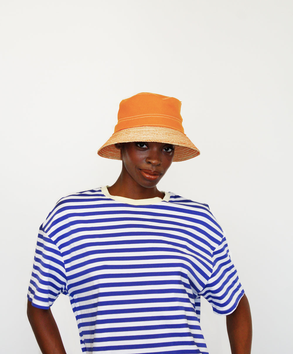 Front view of Chip Bag Hat in apricot showcasing stitched crown and woven brim on model against white background